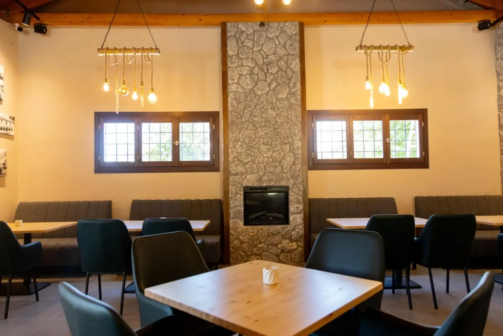 Εσωτερικός χώρος του Cave Garden Bistro με τζάκι, πέτρινη επένδυση και τραπέζια